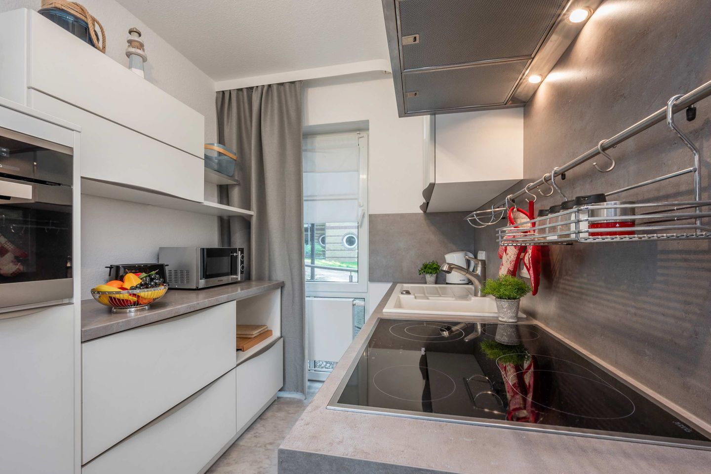 A compact kitchen with a microwave, sink, and stainless steel appliances.