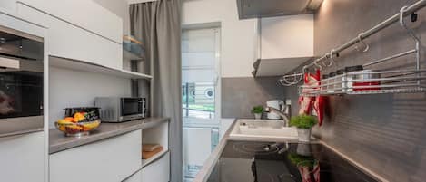 A compact kitchen with a microwave, sink, and stainless steel appliances.
