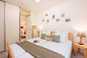 Habitación de hotel con cama, mesitas de noche, un espejo y una puerta que da a un baño.