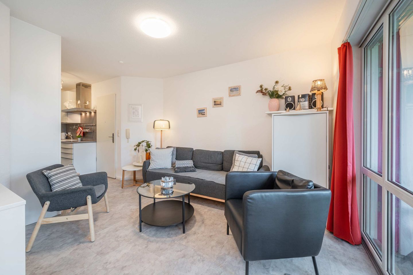 A modern living room with a sofa, armchairs, a coffee table, and a kitchen area in the background.