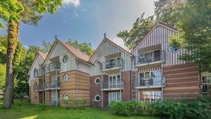 Ein mehrstöckiges Wohngebäude mit Balkonen, einer Ziegel-Fassade und einer umlaufenden Grünfläche.