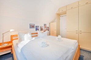 A hotel room with a bed, a nightstand, a lamp, a wardrobe, and wall art.