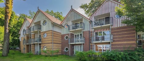 Ein mehrstöckiges Wohngebäude mit Balkonen, einer Ziegel-Fassade und einer umlaufenden Grünfläche.