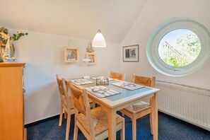 A dining area with a round window, a table with chairs, and a lamp. - Ferienwohnung Zum Seeblick in Koserow - Seeblick Anlage (Koserow)