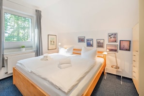 Een hotelkamer met een groot bed, een nachtkastje, een lamp en ingelijste foto's aan de muur.
