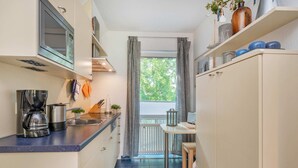 Una cocina compacta equipada con microondas, cafetera y un pequeño comedor con mesa y sillas.