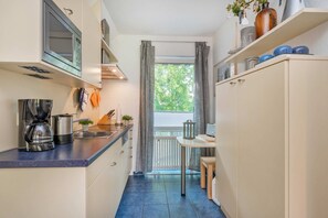 Une cuisine compacte équipée d’un four à micro-ondes, d’une machine à café et d’un petit coin repas avec une table et des chaises.
