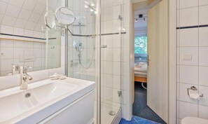 A modern bathroom with a glass-enclosed shower, a white sink, and a mirror.