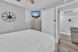 A bedroom with a bed, a TV, a dresser, and a closet. - Sunbird 1010e (Panama City Beach)