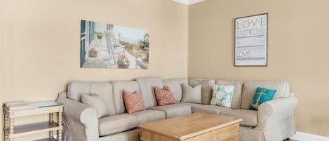 A living room with a beige sofa, a wooden coffee table, and a painting on the wall.