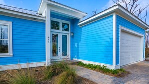 Una casa azul con una puerta de garaje blanca, una puerta principal y un buzón.