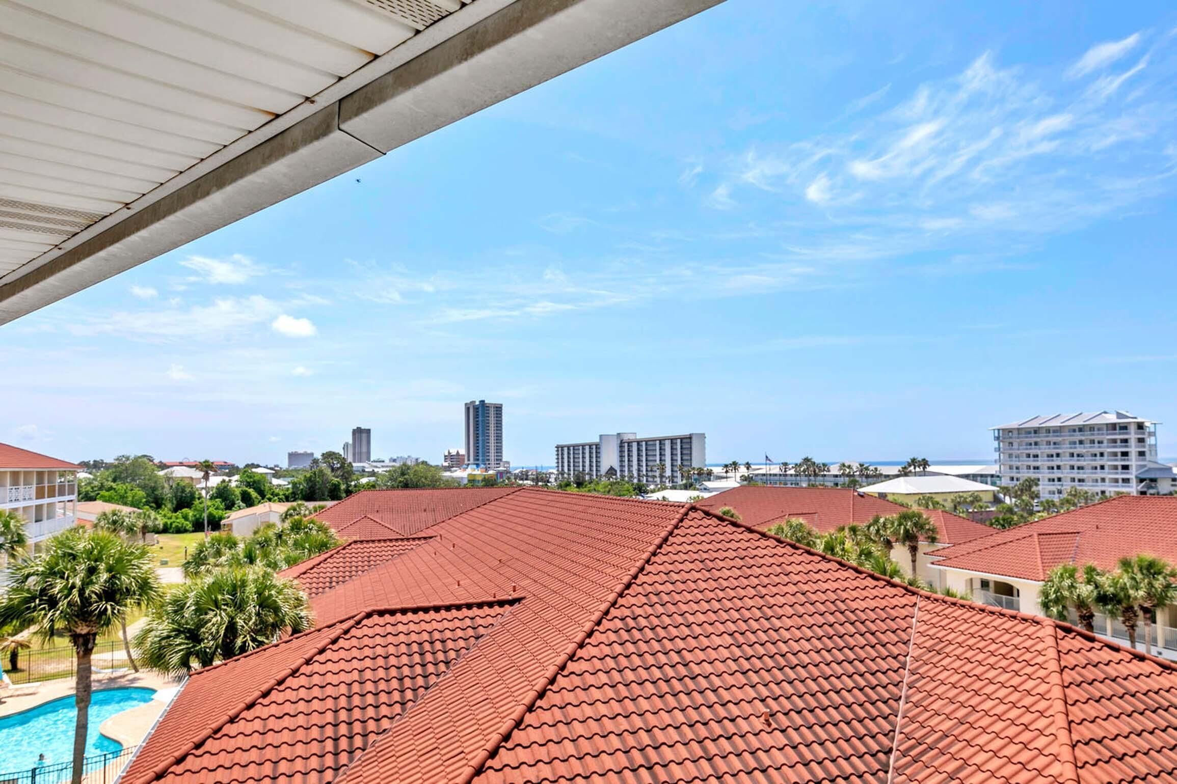 Un complejo turístico con tejados de tejas rojas, piscina y vistas del horizonte urbano.