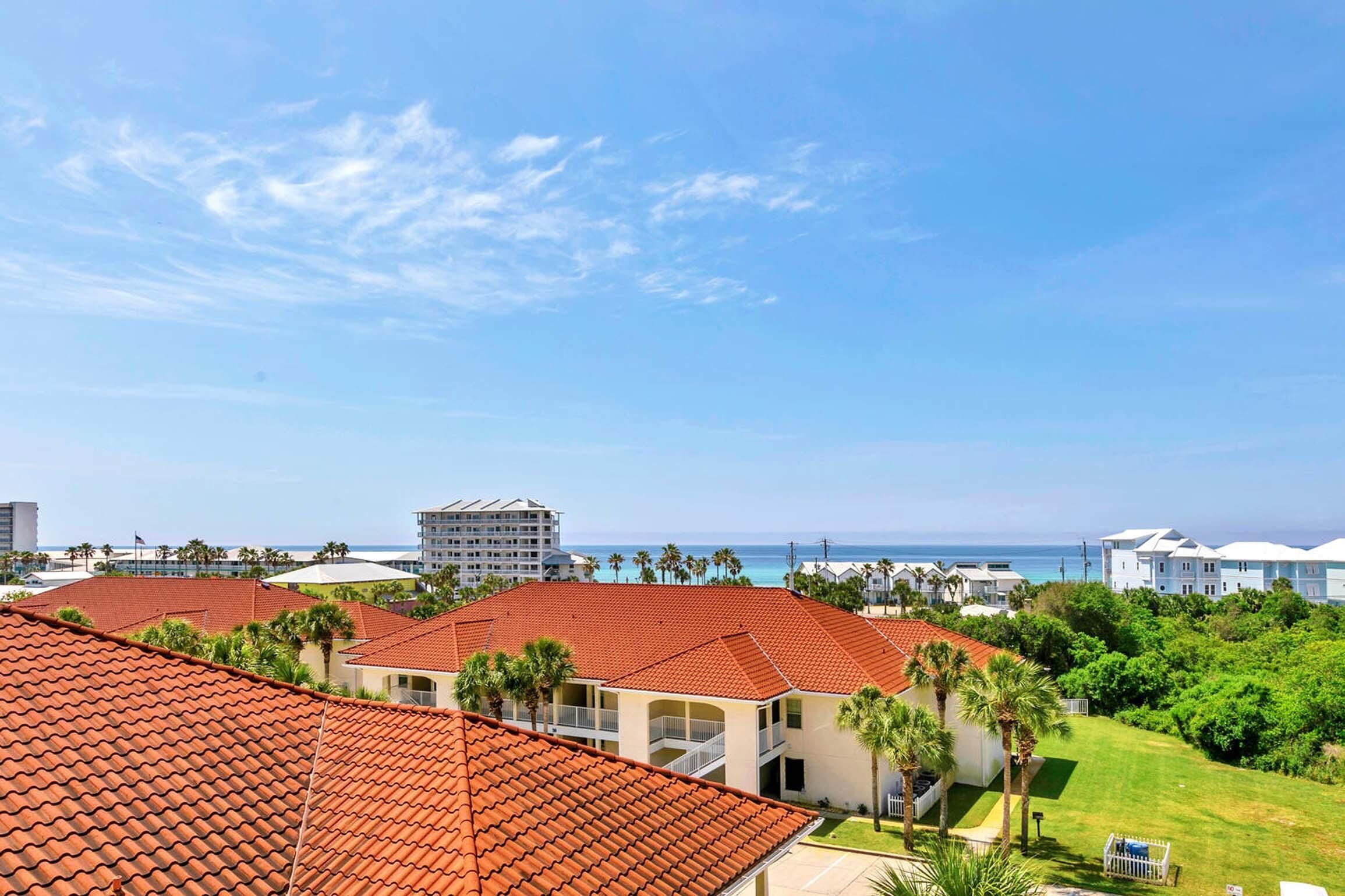 A resort with red-tiled roofs, a pool area, and a view of the ocean.