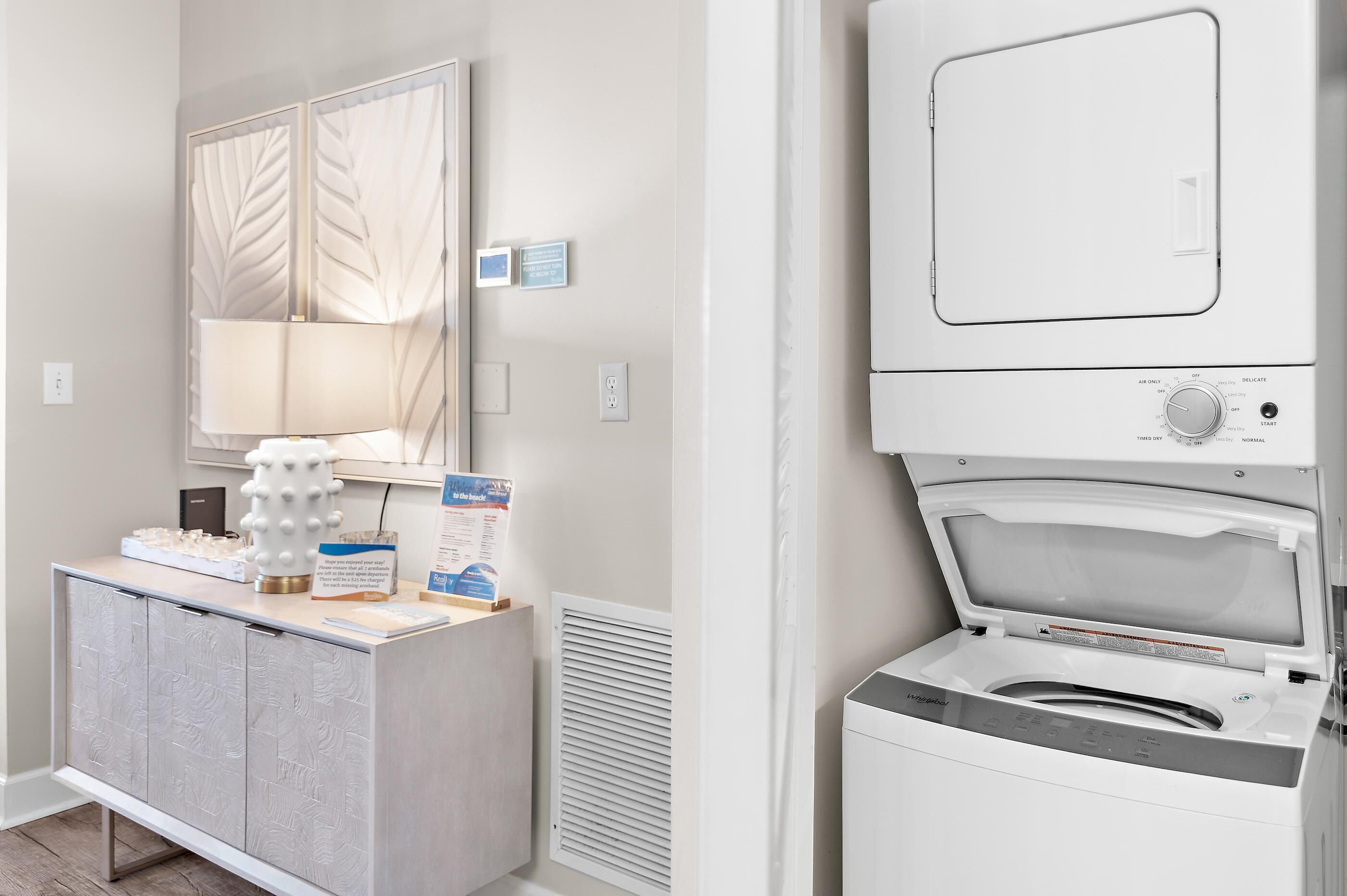 A laundry area with a washing machine, a cabinet with a mirror, and a thermostat on the wall.