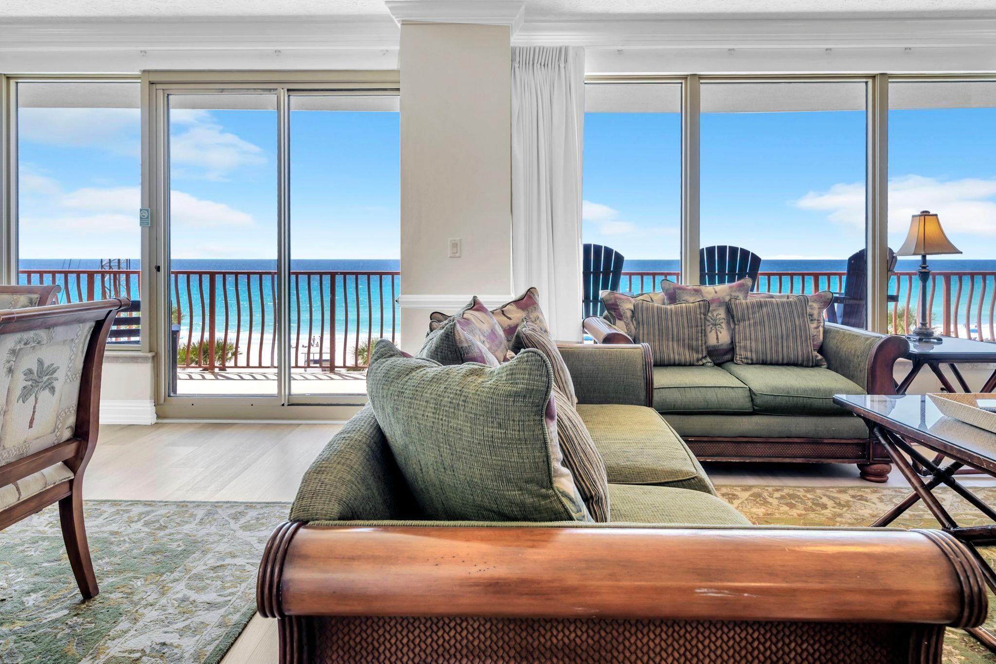A spacious living room with a large sliding glass door leading to a balcony with a view of the ocean.