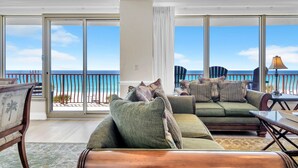 A spacious living room with a large sliding glass door leading to a balcony with a view of the ocean. - Hidden Dunes 405 (Panama City Beach)