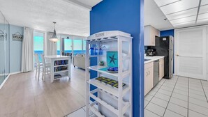 A modern kitchen with a blue accent wall, a white refrigerator, and a coffee machine.