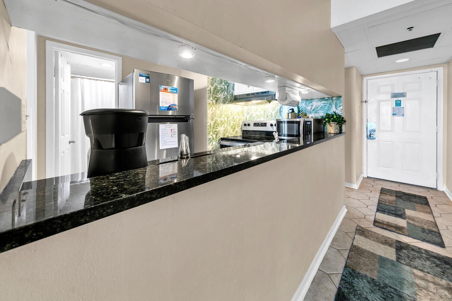 A modern kitchen with a black granite countertop, stainless steel appliances, and a view of the outside.