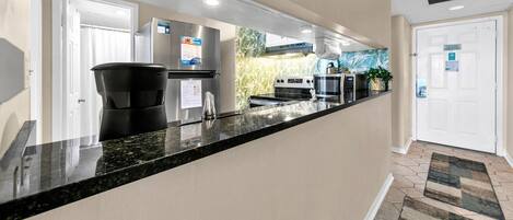 A modern kitchen with a black granite countertop, stainless steel appliances, and a view of the outside.