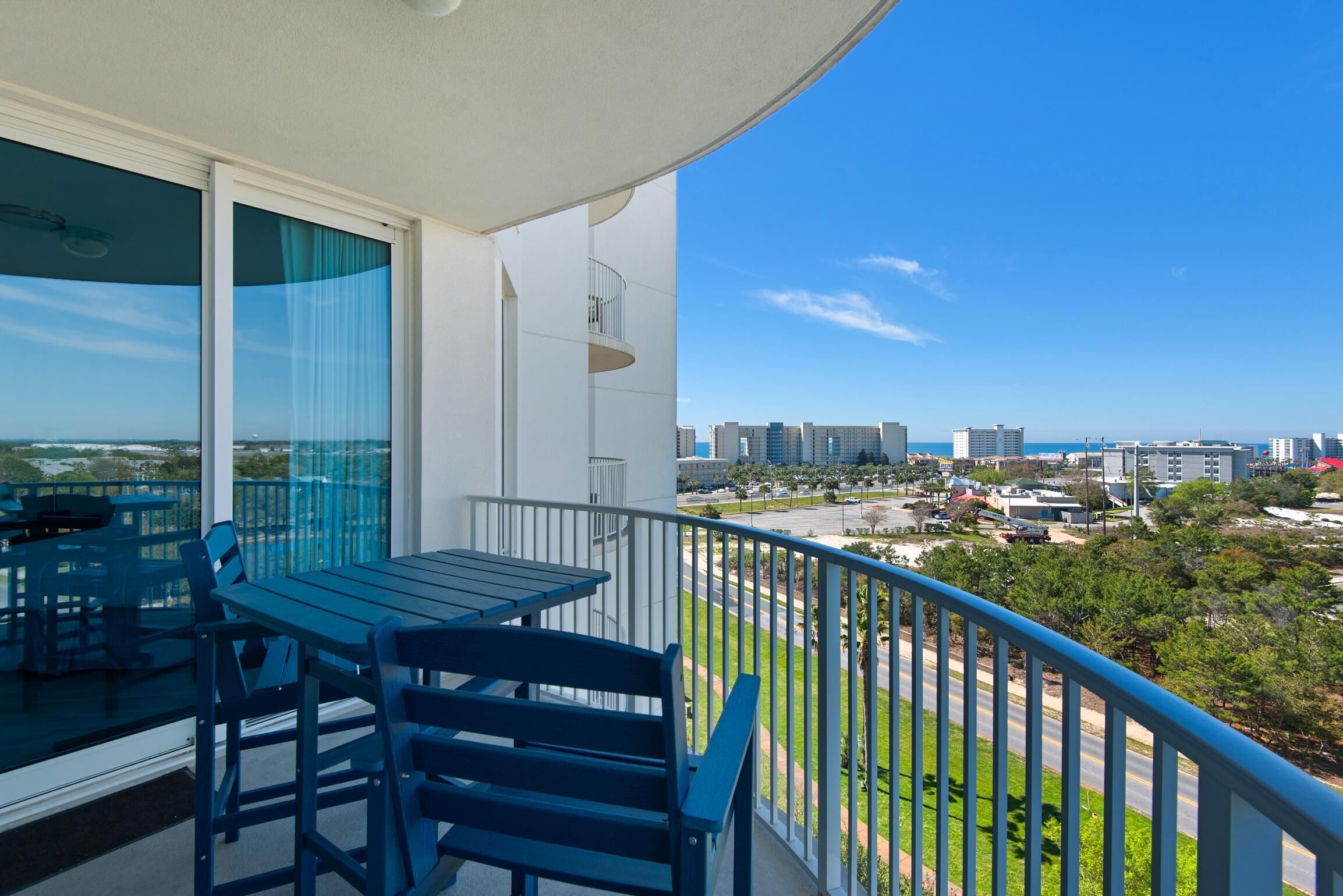 A balcony with a table and chairs, offering a view of a cityscape and a body of water.