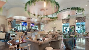 A spacious coffee shop with a modern interior, featuring a bar area, comfortable seating, and a large potted plant. - Palms Resort #2812 Jr. 2br-sunset Dreamer (Destin)