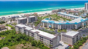 Ett hotellkomplex vid kusten med flera byggnader, en parkeringsplats och utsikt över havet.