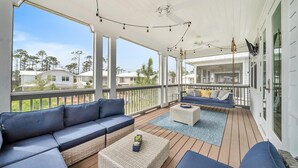 Une véranda avec un canapé bleu, un pouf en osier et une table basse blanche.