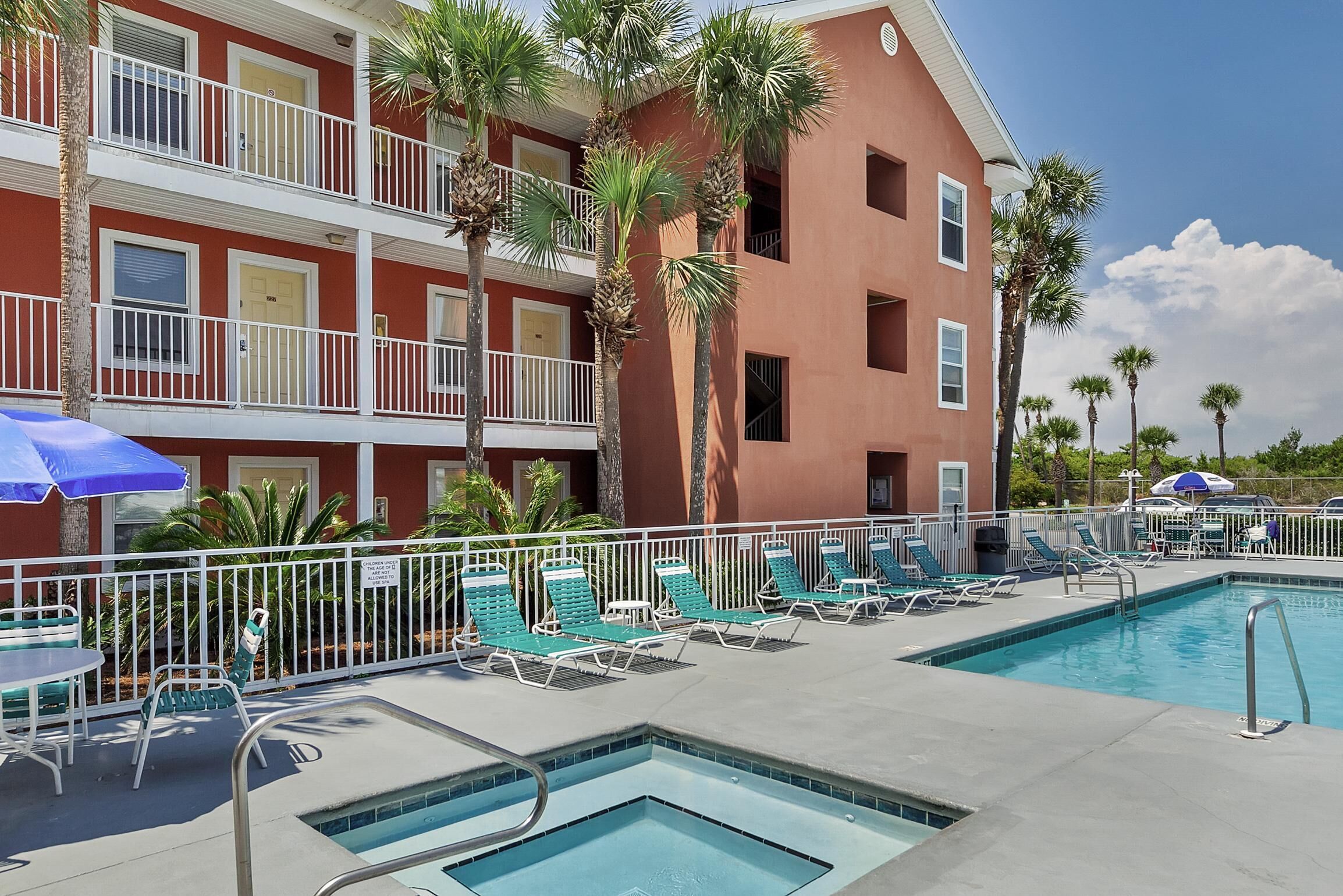 A hotel with a swimming pool, multiple balconies, and palm trees.