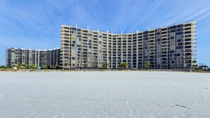 Un hotel moderno con fachada curva, varios balcones y vista al mar.