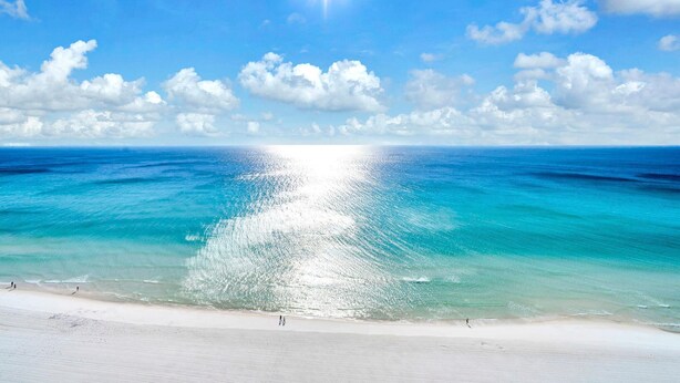 Uma praia com águas turquesa cristalinas e um sol brilhante.