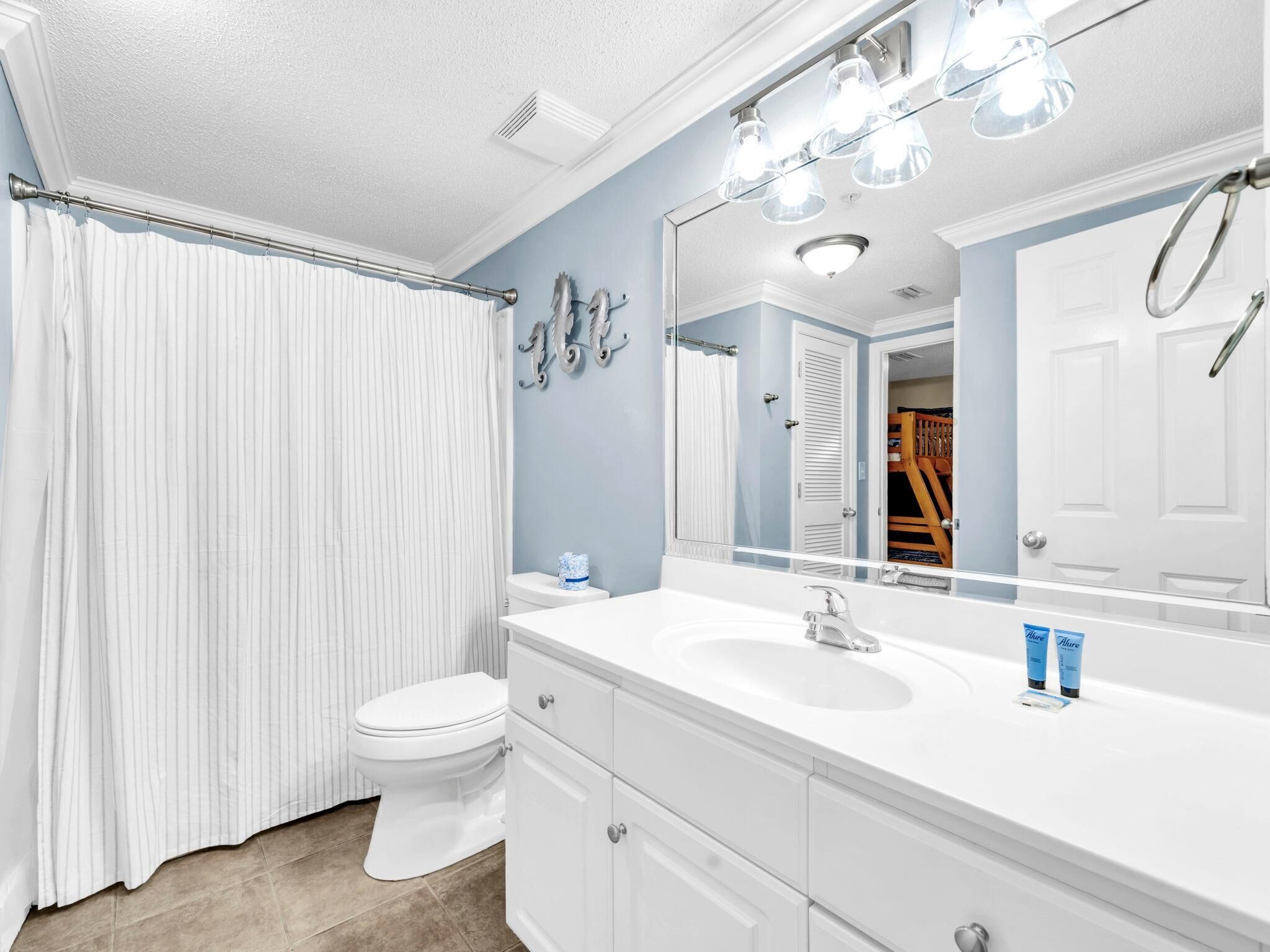 A bathroom with a white vanity, a large mirror, and a shower curtain.