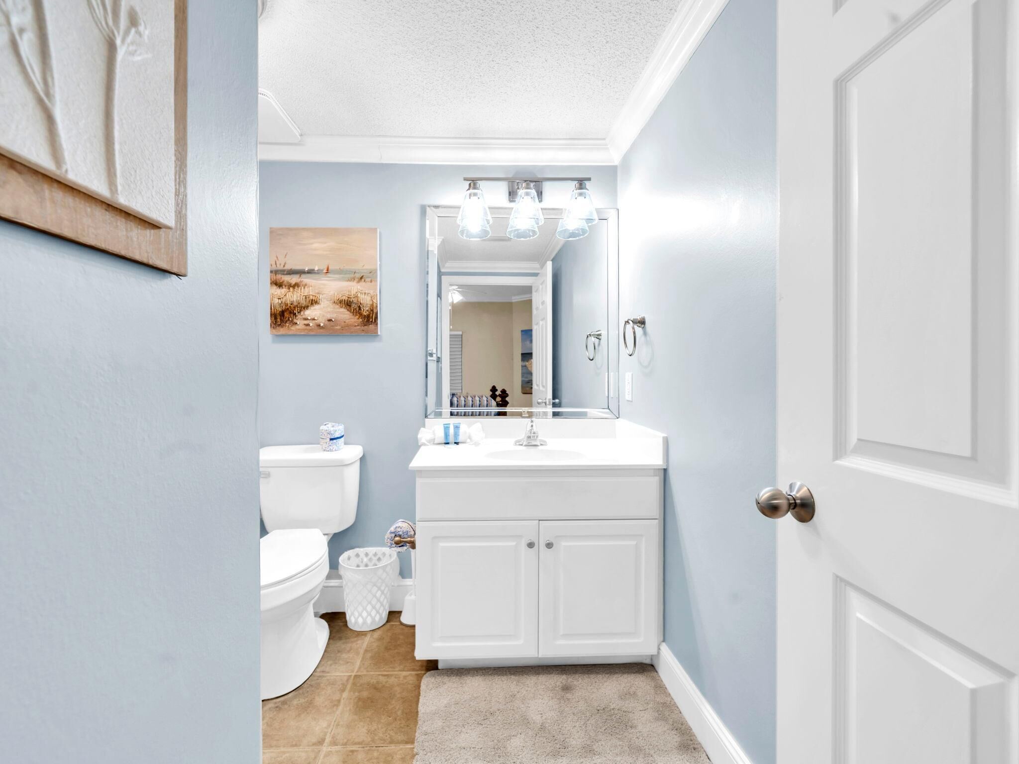 A bathroom with a white toilet, a sink with a mirror, and a door.