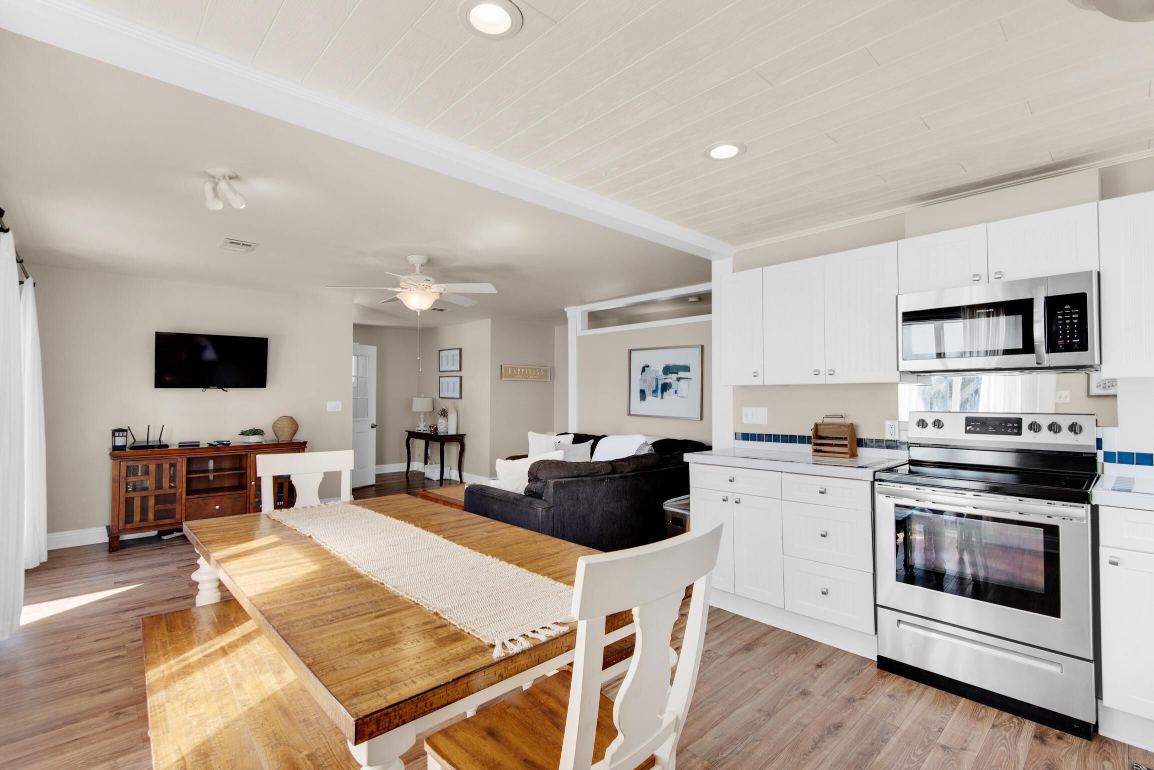 A modern kitchen with white cabinetry, a wooden dining table, and a built-in oven.