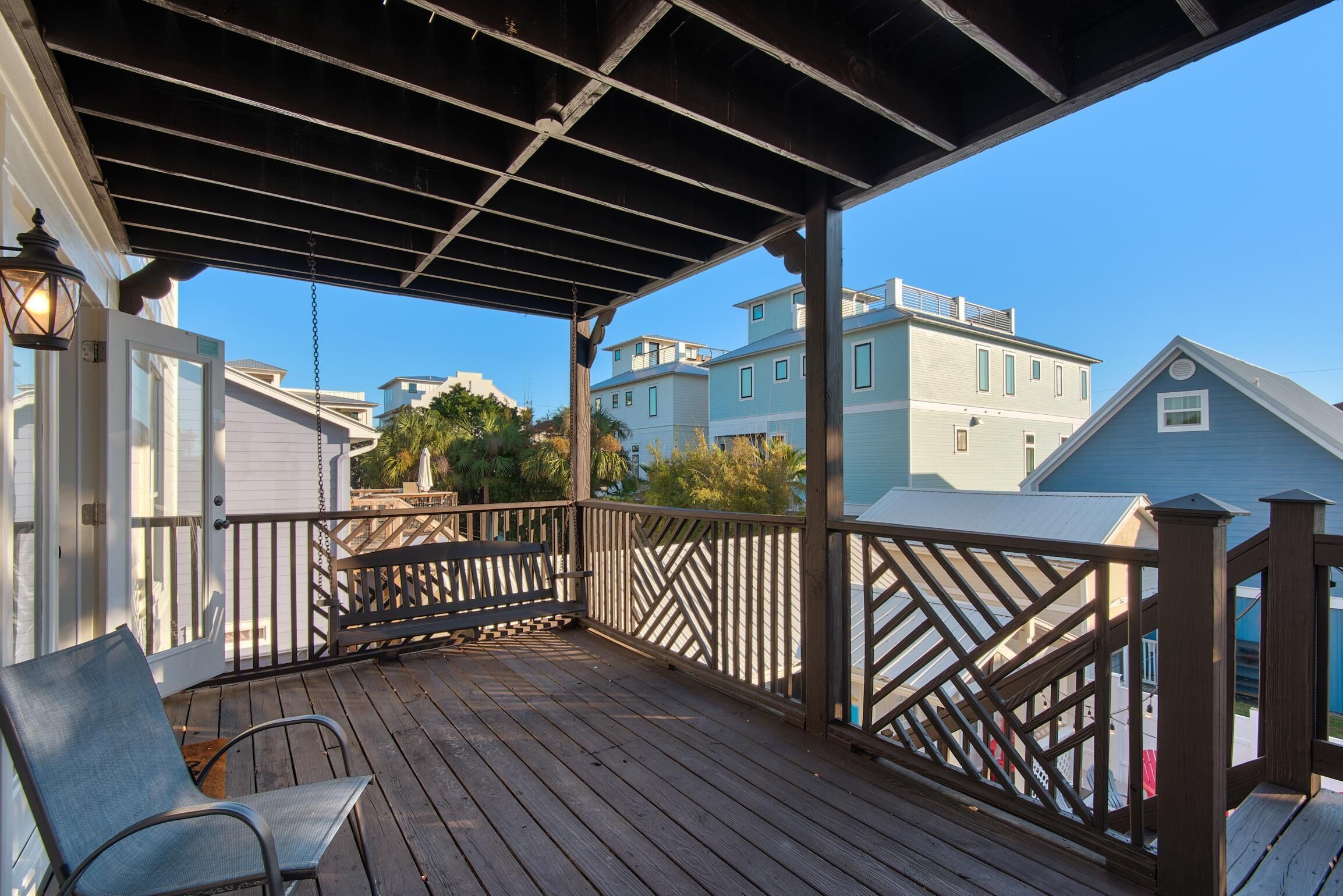 A wooden deck with a railing, a bench, and a hanging lantern.