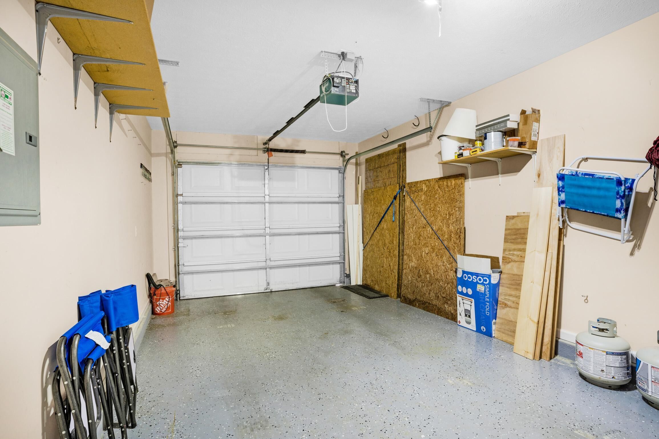 A garage with a white door, a ceiling-mounted projector, and various tools and materials on the walls.