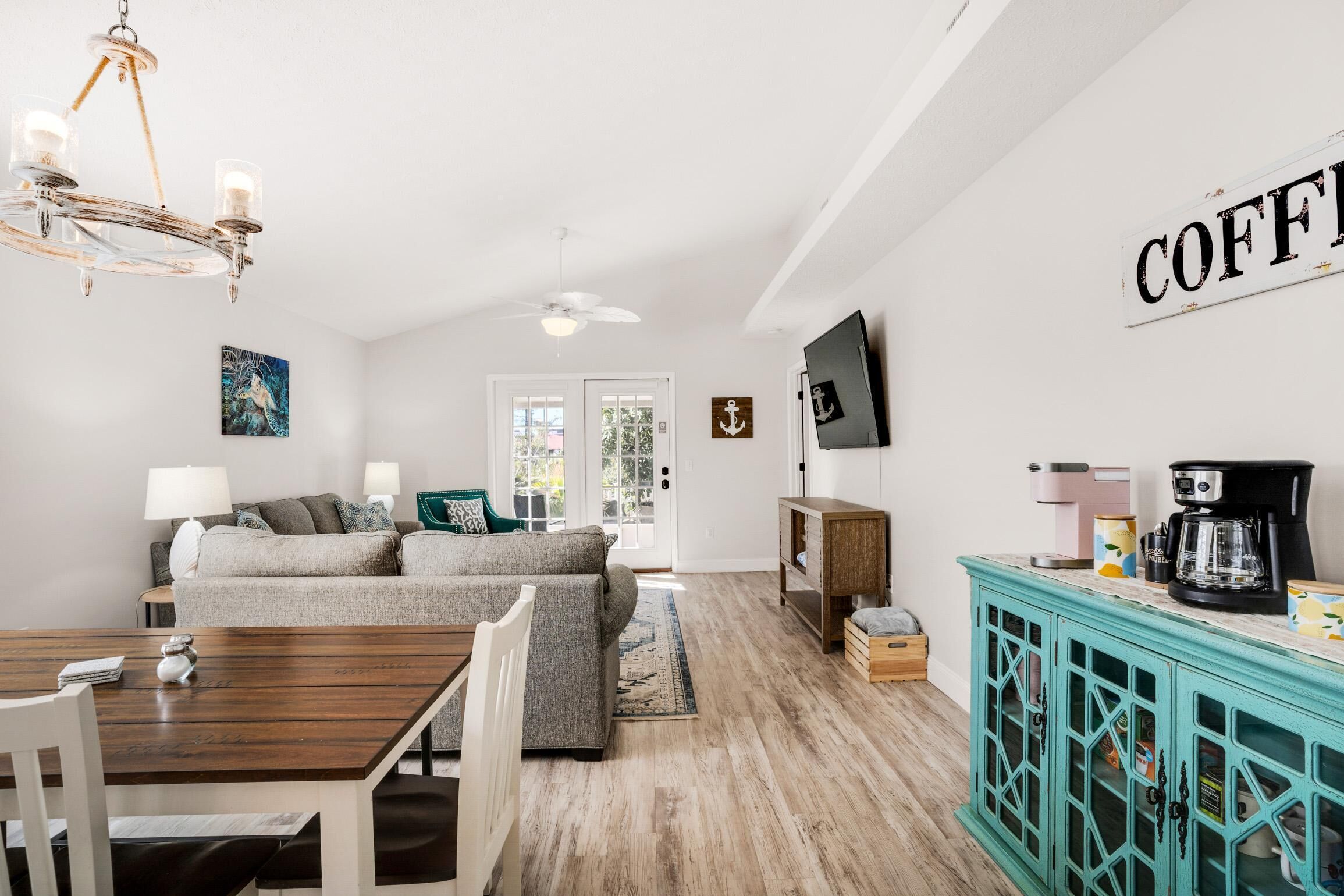A living room with a sofa, coffee table, and a teal cabinet with a coffee machine.