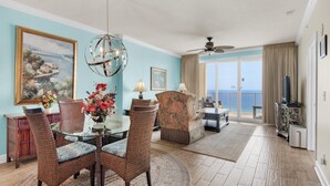 A spacious living room with a dining area, a large painting, and a view of the ocean.