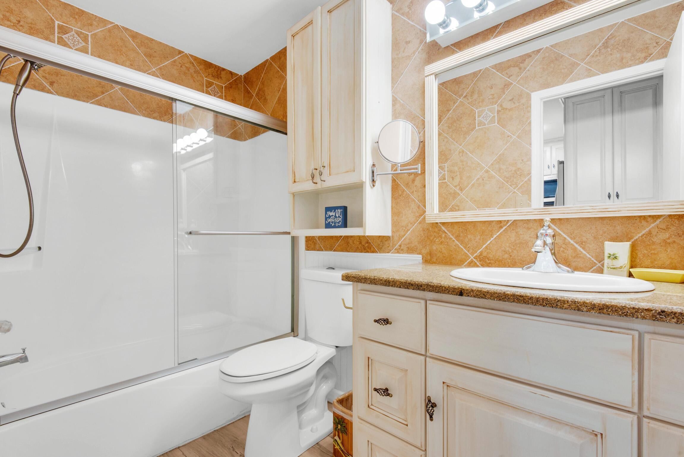 Un baño moderno con ducha envuelta en vidrio, inodoro blanco y tocador con lavabo y espejo.