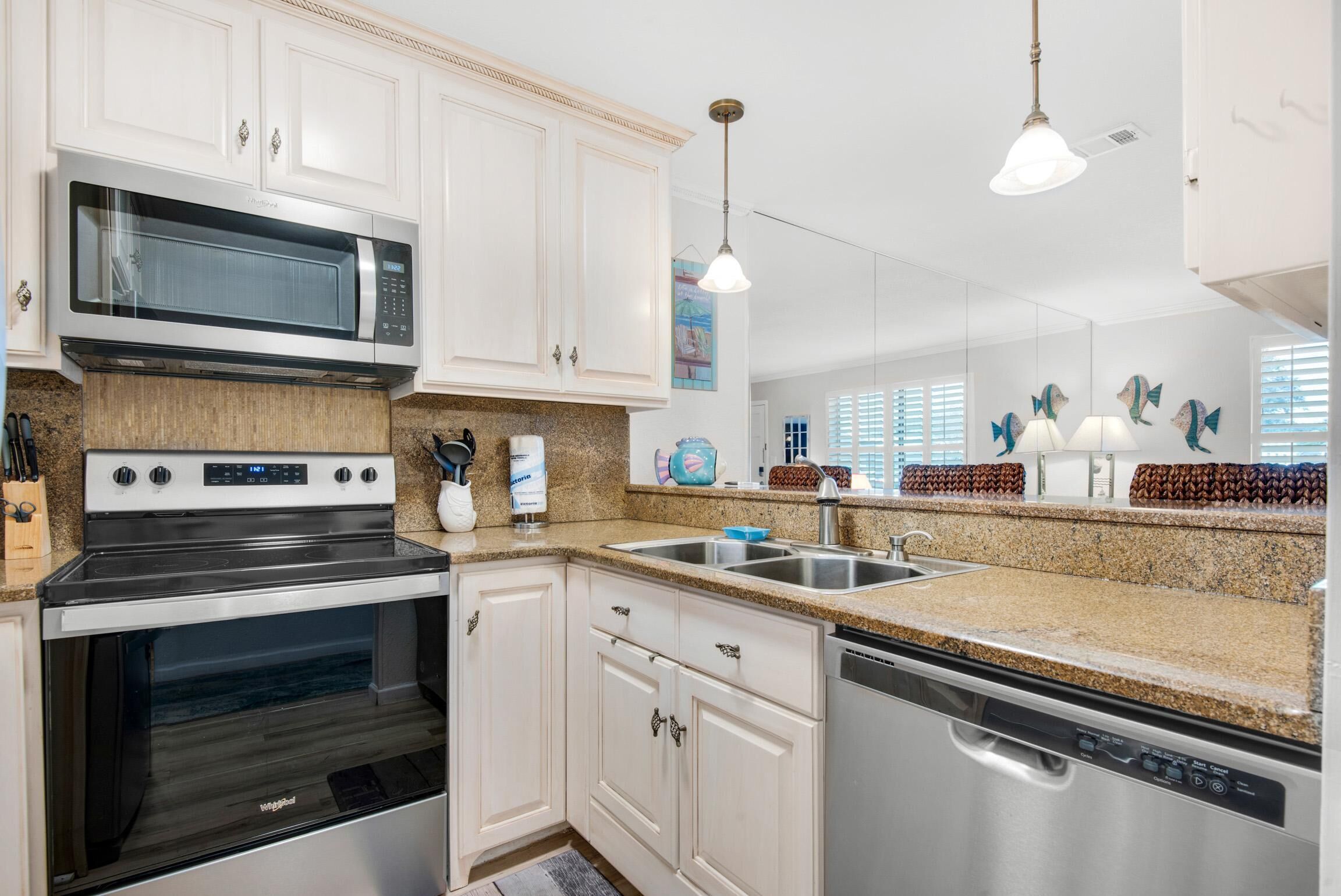 A modern kitchen with white cabinets, stainless steel appliances, granite countertops, and decorative fish wall art.