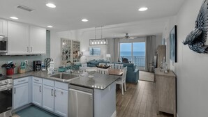 Una cocina moderna con gabinetes blancos, una isla central y un comedor con mobiliario azul.