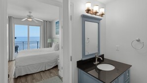 Habitación de hotel con cama, baño con lavamanos y espejo, y vista al océano.