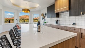 A modern kitchen with a large island, wooden cabinets, and a view of the desert landscape. - 3 Miles from Bell Rock| Hot Tub| Pool Table| Sleeps 14 (Sedona)