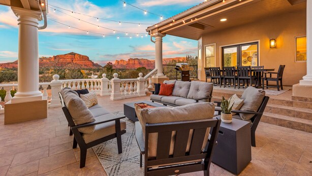 An outdoor patio area with a sofa set, dining table, and chairs, overlooking a scenic view of red rock formations. - 3 Miles from Bell Rock| Hot Tub| Pool Table| Sleeps 14 (Sedona)