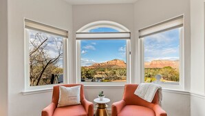 A room with two orange chairs, a small table, and a view of a mountainous landscape through large windows. - 3 Miles from Bell Rock| Hot Tub| Pool Table| Sleeps 14 (Sedona)