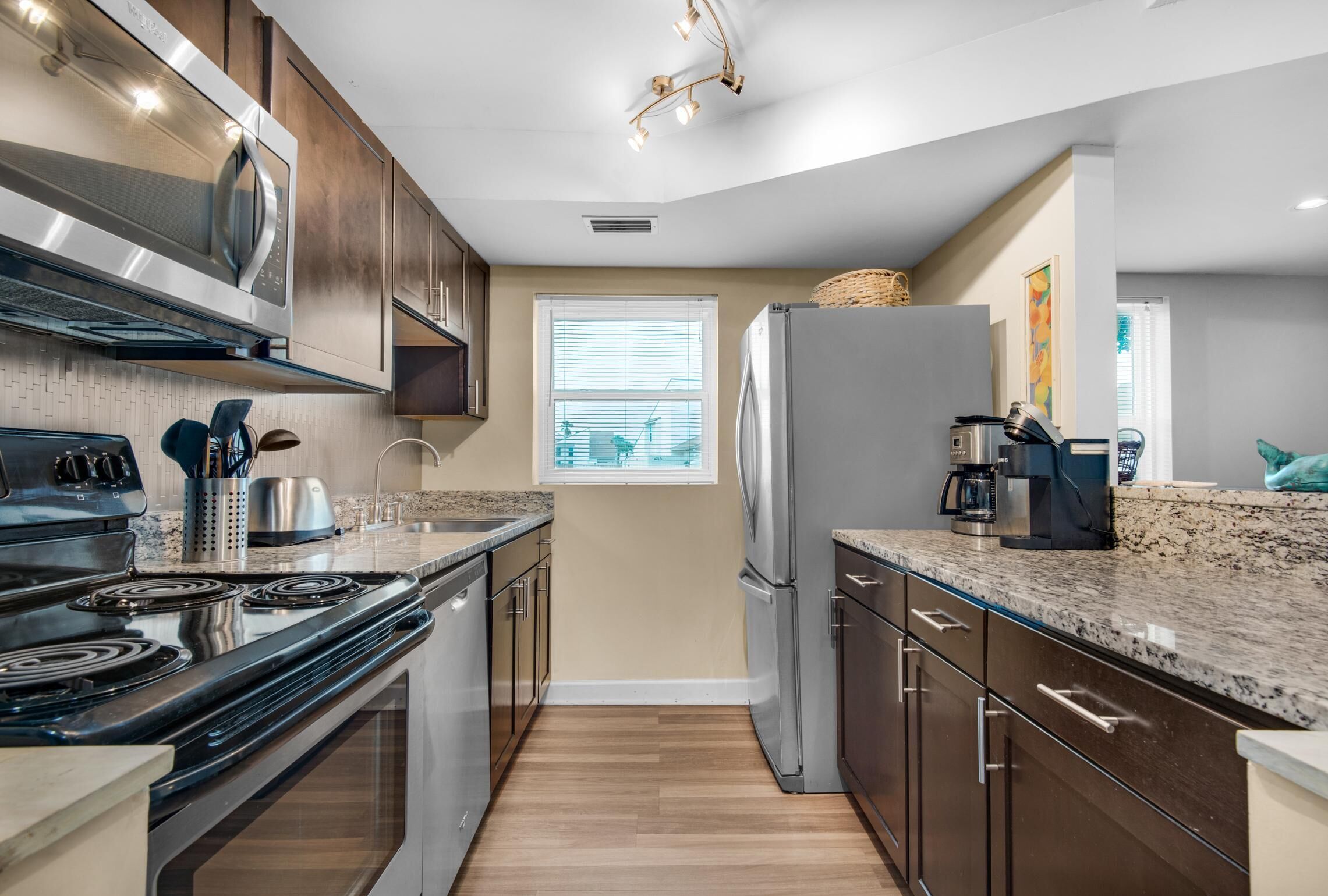 A modern kitchen with stainless steel appliances, wooden cabinets, and a granite countertop.