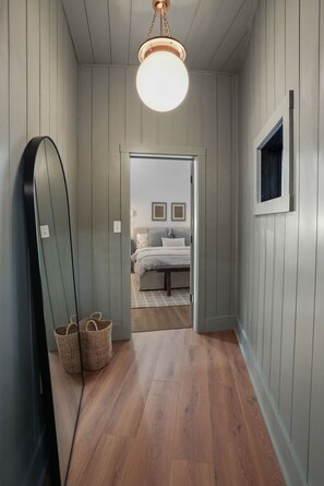 Un couloir doté d’un plancher en bois, d’un grand miroir et de paniers en osier.