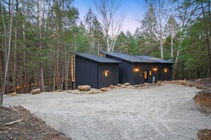 Une cabane avec une allée en gravier, entourée d’arbres.