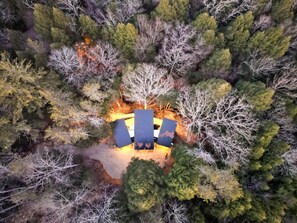 An aerial view of a campsite with a central fire pit surrounded by trees.
