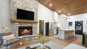 Una sala de estar moderna con chimenea de piedra, un televisor de pantalla plana y una zona de estar acogedora.