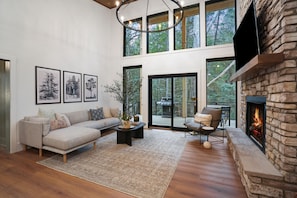 A spacious living room with a stone fireplace, large windows, and a cozy seating area.
